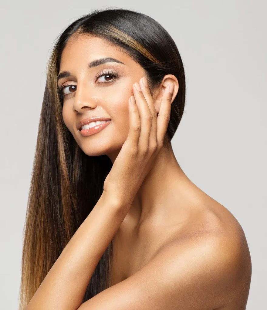 A smiling woman touches her smooth face, highlighting the effects of Medical-Grade Facial in Bellmore, NY