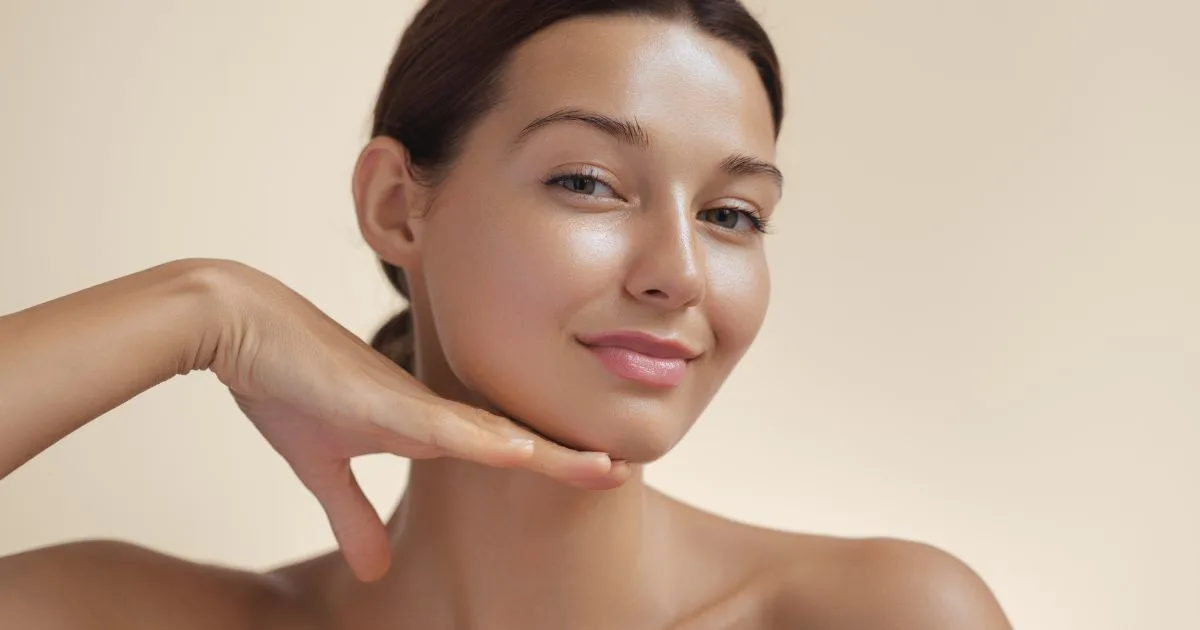 Woman smiling while receiving a calming mask application after a facial exfoliation treatment like dermaplaning.